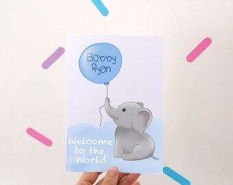 Puede incluir: Una tarjeta azul y blanca con una ilustración de un elefante gris sosteniendo un globo azul. El globo tiene el texto "Bobby Ryan" en él. La tarjeta también tiene el texto "Bienvenido al mundo".