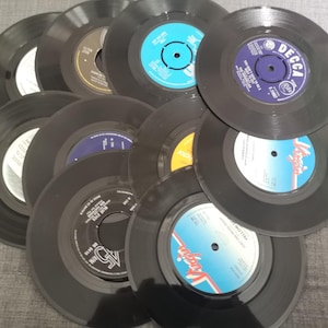 May include: A collection of vintage 45 rpm vinyl records with various labels and artists. The records are black with colourful labels featuring text and images.