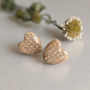 Op de afbeelding: Een paar hartvormige oorbellen met een gespikkeld beige en bruin glazuur.