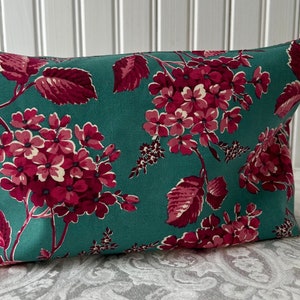 May include: Teal zippered pouch with a floral print featuring pink and red flowers and leaves.
