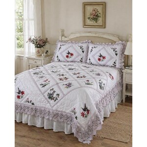 May include: White quilt set with floral and hummingbird embroidery. The quilt features a grid pattern with embroidered squares, a ruffled edge, and matching pillow shams. The bedding set is designed for a bed and includes a bed skirt.