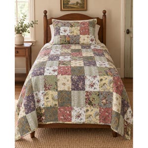 May include: A twin-sized bed featuring a wooden headboard and a patchwork quilt with a matching pillow sham. The quilt displays a repeating pattern of square fabric patches in muted shades of sage green, dusty rose, cream, and deep purple.