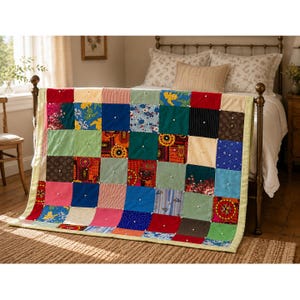 May include: A patchwork quilt featuring a grid of multi-colored fabric squares in various patterns including floral, striped, and solid designs. Each square is accented with a small white button at its center, and the quilt is finished with a light yellow border.
