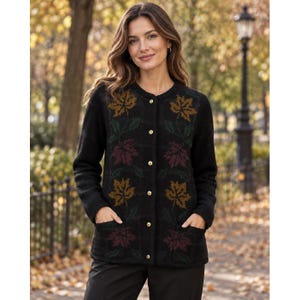 May include: A black long-sleeve cardigan featuring a round neckline, a front button closure with gold-toned buttons, and two front pockets. The knit fabric displays a repeating pattern of autumn maple leaves in shades of gold, burgundy, and green.