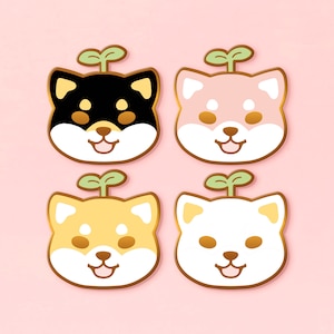 Puede incluir: Cuatro diseños de caras de perros Shiba Inu de dibujos animados en negro, rosa, amarillo y blanco, cada uno con un brote verde en la parte superior. Los perros tienen acentos marrones y están delineados en marrón. El fondo es rosa claro.
