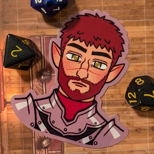 May include: A sticker of a cartoon character with red hair, a beard, and pointed ears. The character is wearing a purple and white armor. The sticker is on a wooden surface with dice.