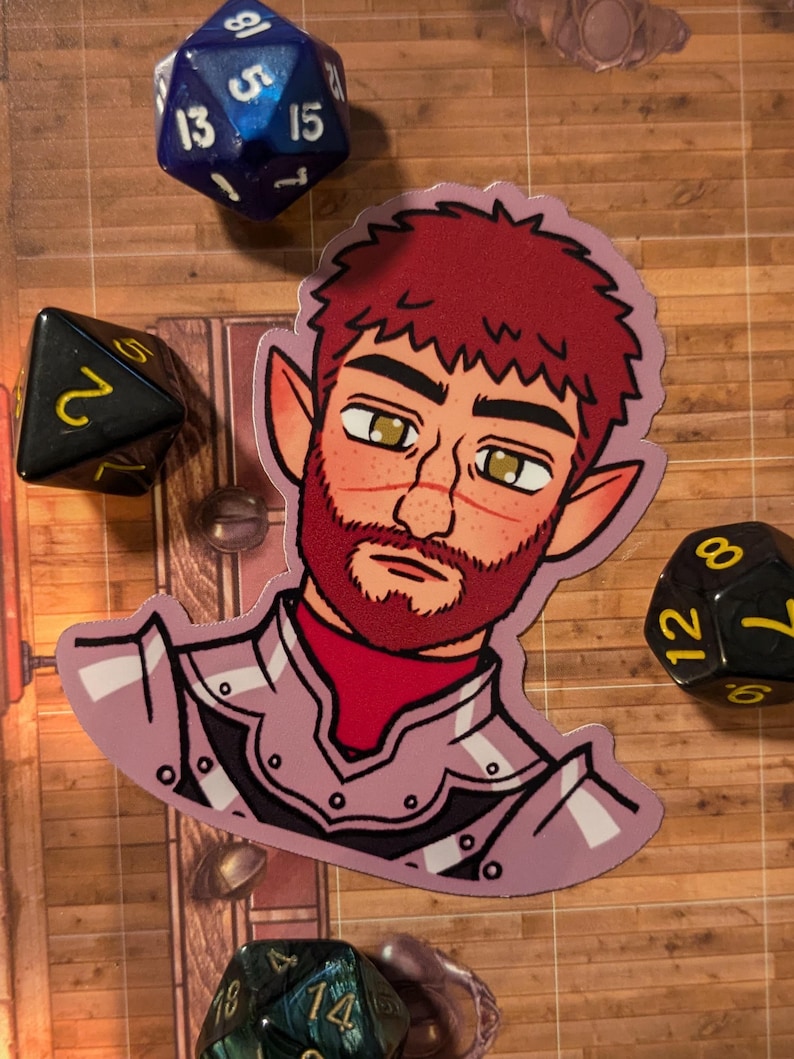 May include: A sticker of a cartoon character with red hair, a beard, and pointed ears. The character is wearing a purple and white armor. The sticker is on a wooden surface with dice.