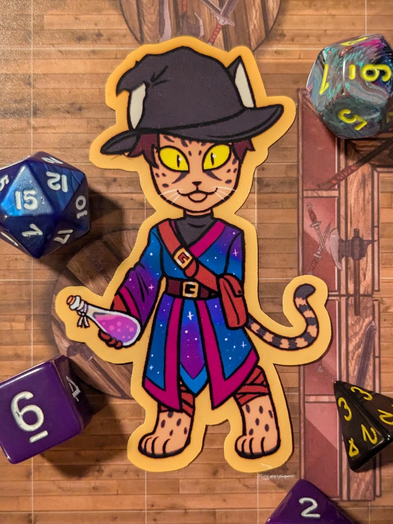 May include: A sticker of a cartoon cat wearing a wizard hat and robe. The cat is holding a potion bottle and has a starry sky pattern on its robe. The sticker is on a wooden background with dice.