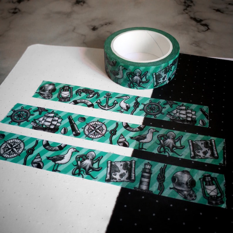 May include: A roll of green and white washi tape with a nautical theme. The tape features a variety of nautical symbols, including anchors, compasses, ships, and seagulls. The tape is ideal for adding a touch of nautical charm to your crafts and projects.