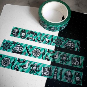 May include: Five rolls of washi tape with a nautical theme. The tape features a variety of designs, including anchors, ships, compasses, and sea creatures. The tape is green and white with black accents.