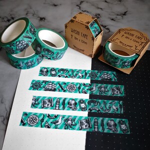 May include: Five rolls of green and black washi tape with nautical themed designs. The tape is 10mm x 15mm and is packaged in brown boxes with the text "Washi Tape 10mm x 15mm Rockabillyville" printed on them.