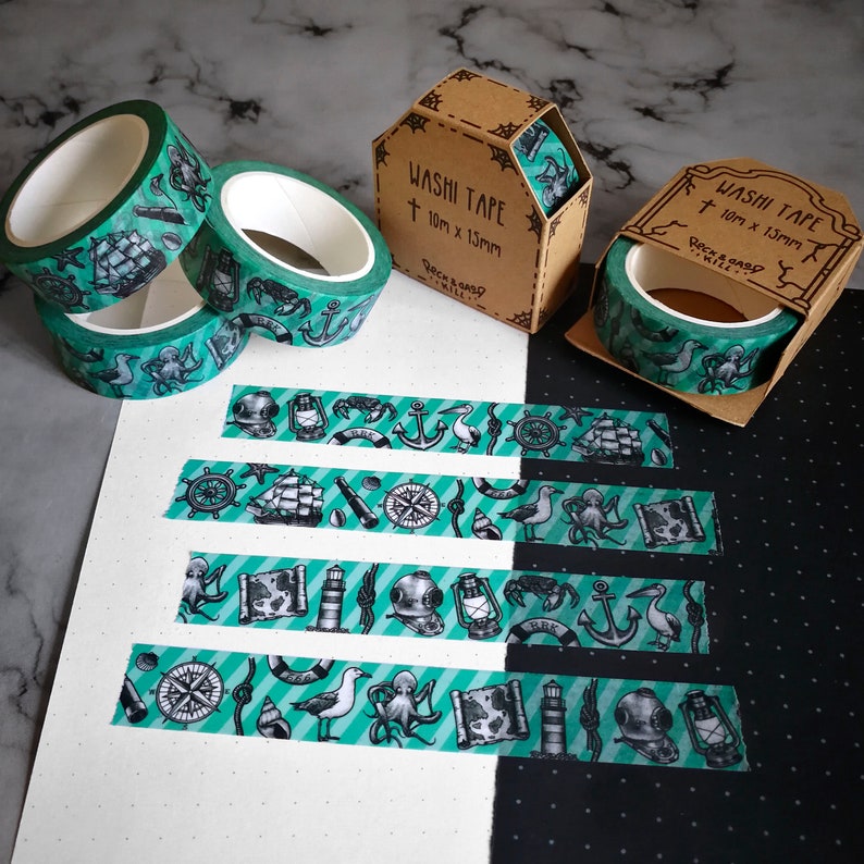May include: Five rolls of green and black washi tape with nautical themed designs. The tape is 10mm x 15mm and is packaged in brown boxes with the text "Washi Tape 10mm x 15mm Rockabillyville" printed on them.