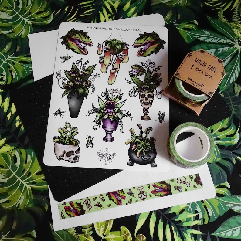 Op de afbeelding: Een set van 14 stickers met illustraties van vleesetende planten in verschillende poses. De stickers bevinden zich op een wit vel papier met een zwarte achtergrond. De stickers zijn omringd door groene bladeren. De stickers zijn te koop op Etsy. De tekst op het vel papier luidt "@rockandroakkillofficial".