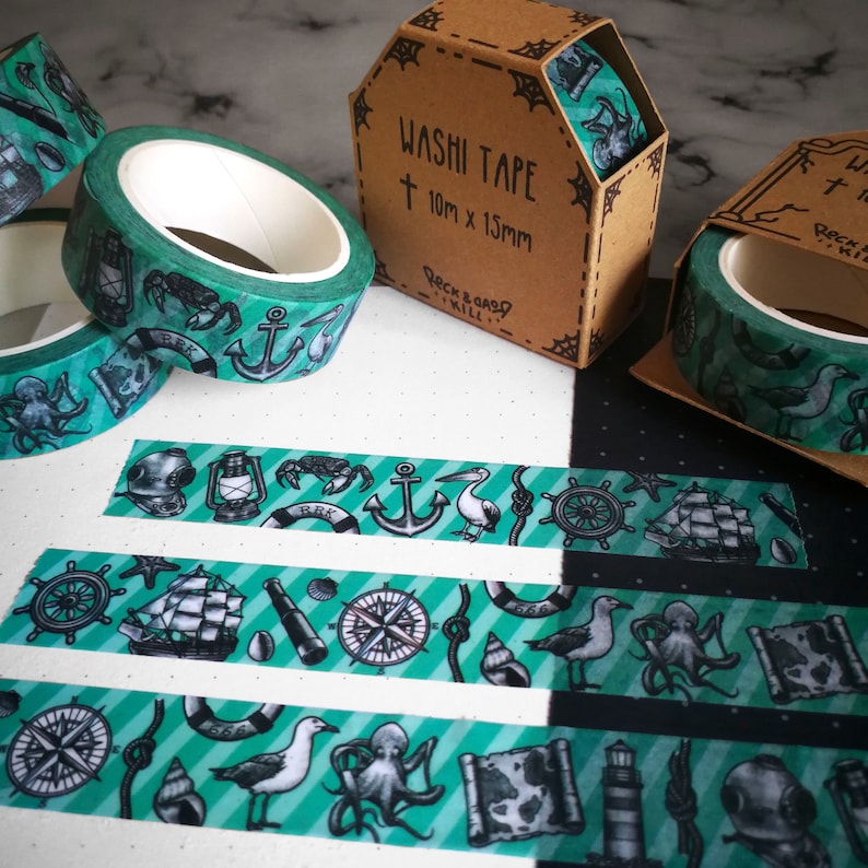 May include: A set of three green and black washi tapes with nautical themed illustrations. The tapes feature a compass, anchor, ship, octopus, seagull, and lighthouse. The tapes are 10mm wide and 15mm long. The packaging is brown with white text that reads "Washi Tape 10m x 15mm Rock & Coast Will."
