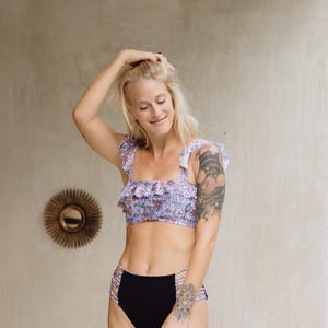 K&ouml;nnte beinhalten: Ein zweiteiliger Badeanzug bestehend aus einem bauchfreien Oberteil mit Blumenmuster, ger&uuml;schten Schultertr&auml;gern und einem ger&uuml;schten Ausschnitt. Das passende hoch taillierte Bikiniunterteil ist schwarz und hat seitliche Cut-outs.