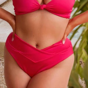May include: A bright fuchsia bikini set featuring a high-waisted bottom with a distinctive V-shaped crossover front waistband and a matching bikini top with a central knot detail, crafted from a smooth, solid-colored fabric.