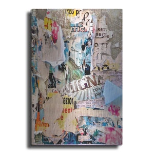 May include: A close-up of a wall covered in colorful, torn, and layered posters. The posters are in Italian and feature a variety of images and text. The wall is a textured, light gray color.