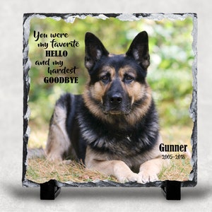 May include: A black and brown German Shepherd dog lying down on a bed of green grass. The dog is looking directly at the camera. The image is a memorial for a dog named Gunner, who lived from 2005 to 2016. The text "You were my favorite hello and my hardest goodbye" is printed on the image.