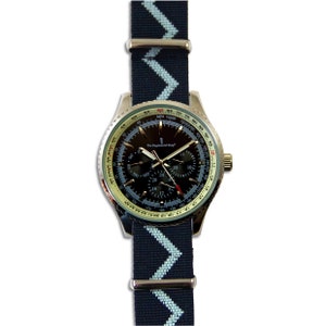 Op de afbeelding: Een zilverkleurig chronograafhorloge met een zwarte wijzerplaat en een zwart-witte chevron-gepatenteerde band. De wijzerplaat van het horloge heeft meerdere subwijzerplaten en de tekst "The Regimental Shop".