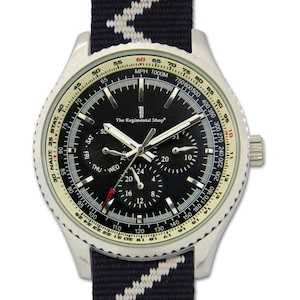 May include: A silver wristwatch with a black face and a navy blue and white striped strap. The watch face displays multiple sub-dials, including day and date indicators, and the text "The Regimental Shop". The watch has a rotating bezel with speed markings.