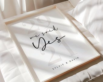 May include: A white framed print with the text "We said Yes" and the year "2021" in a large, gray font. The names "Sylvie & David" are printed in a smaller font at the bottom of the print.