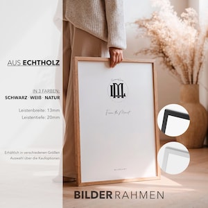 May include: A wooden picture frame with a white mat and a black logo. The frame is held by a person. The frame is available in black, white, and natural wood. The frame's dimensions are 13mm wide and 20mm deep. The text on the frame says "Frame the Moment."