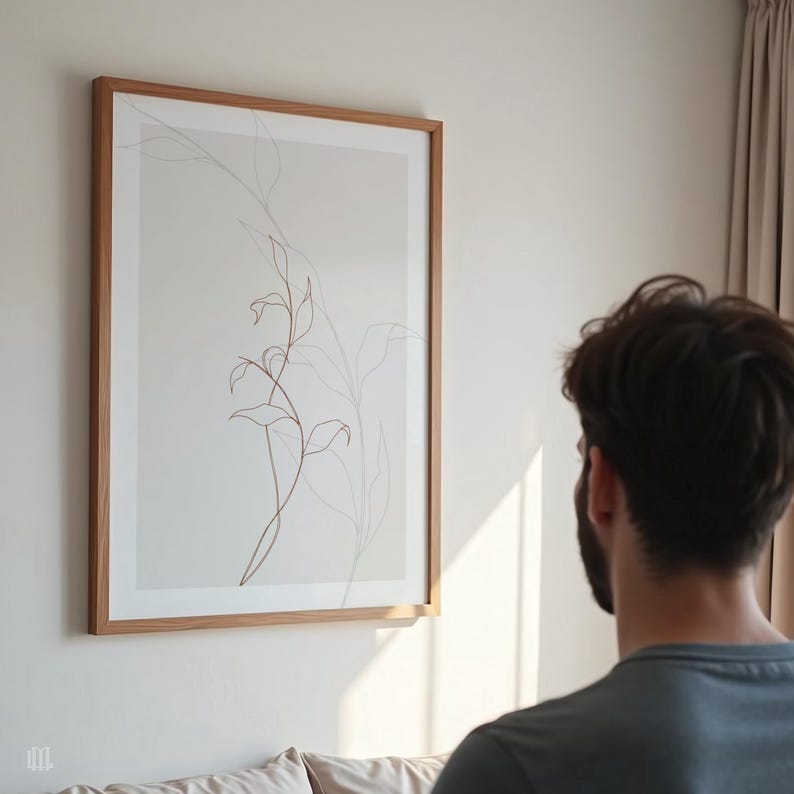 May include: A framed botanical print featuring delicate line art of leaves and stems in shades of brown and gray. The artwork is encased in a light brown wooden frame and hangs on a white wall.