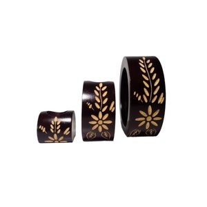 Peut inclure: Ensemble de trois bougeoirs en bois brun avec un motif floral. Les bougeoirs sont de tailles diff&eacute;rentes et sont dispos&eacute;s en rang&eacute;e du plus grand au plus petit.