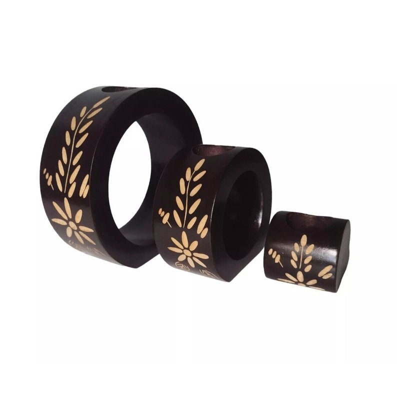 Peut inclure: Ensemble de trois bougeoirs en bois avec un motif floral. Les bougeoirs sont de couleur marron avec des accents floraux dor&eacute;s et sont de tailles diff&eacute;rentes.