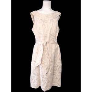 May include: A sleeveless white dress with a floral pattern and a matching belt. The dress has a scoop neck and a fitted bodice.