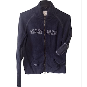 Könnte beinhalten: Ein dunkelblauer Reißverschluss-Pullover mit dem Wort "MINNIE" auf der Vorderseite gestickt. Der Pullover hat einen gerippten Kragen und Bündchen sowie einen Patch am linken Ellbogen.