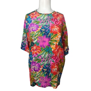 May include: A colorful, floral print shirt with short sleeves. The shirt is made of a silky material and features a variety of flowers and leaves in shades of pink, red, orange, yellow, green, blue, and purple.