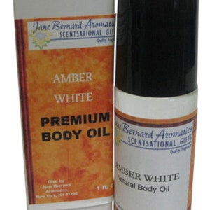 Könnte beinhalten: Eine Glasflasche mit Amber White Premium Body Oil mit einem weißen Etikett und einem schwarzen Deckel. Das Etikett trägt den Text "Jane Bernard Aromatics ScentSational Gifts" und "Amber White Premium Body Oil".