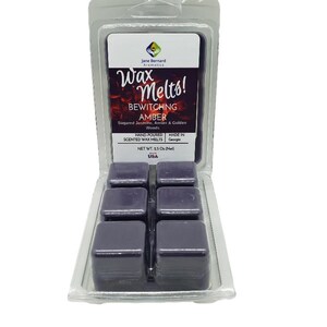 May include: A clear plastic package containing six dark purple wax melt cubes. The label reads "Wax Melts! BEWITCHNG AMBER" with scent notes. The product is hand-poured and made in Georgia, USA. Net weight is 2.5 oz.