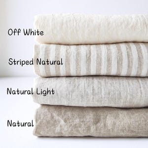 Könnte beinhalten: Ein Stapel von vier gefalteten Leinenstoffmustern in verschiedenen neutralen Farben. Die Farben sind mit "Off White", "Striped Natural", "Natural Light" und "Natural" beschriftet. Der Text oben weist darauf hin, dass der Stoff aus 100 % Leinen und von mittlerem Gewicht ist.