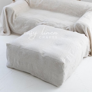 Könnte beinhalten: Ein großes, cremefarbenes Leinen-Sofa mit einer passenden Leinen-Ottomane. Das Sofa ist mit einer lockeren Leinen-Decke bedeckt. Die Ottomane befindet sich im Vordergrund und das Sofa im Hintergrund. Der Text "easy linen crafts" ist auf der Ottomane sichtbar.