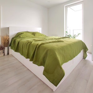 a bed with a green comforter on top of it