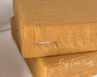 May include: Two mustard yellow linen floor cushions with zippers. The cushions are stacked on top of each other. The text "Easy Linen Crafts" is visible on the bottom cushion.