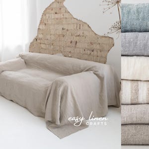 May include: A light beige linen throw blanket draped over a sofa. The sofa is in front of a brick wall. The throw blanket is made by Easy Linen Crafts.
