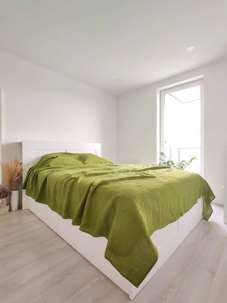 a bed with a green comforter on top of it