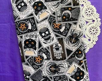 May include: Black and white fabric with a repeating pattern of tarot cards. The cards feature images of a black cat, a skull, a spider, a pentagram, a crescent moon, and a hand with an eye. The text on the cards includes "The Black Cat", "The Moon", and "Black Cat".