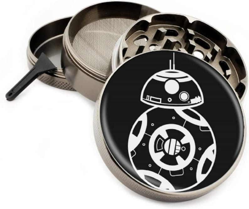 Puede incluir: Un molinillo de metal plateado con un dise&ntilde;o en blanco y negro del personaje de Star Wars BB-8. El molinillo tiene una malla, un compartimento para hierbas y un compartimento para recoger kief.