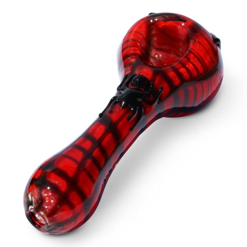 May include: A red glass pipe with a black spider design. The pipe is made of glass and has a bowl on one end and a mouthpiece on the other.