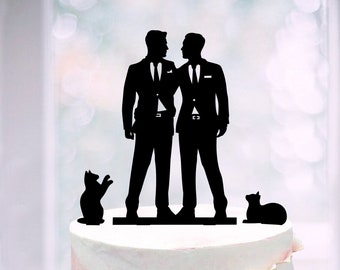 Könnte beinhalten: Eine weiße Hochzeitstorte mit rosa Marmorierung und goldenen Akzenten. Die Torte ist mit Blumen und einem schwarzen Silhouetten-Tortenaufsatz aus zwei Bräutigamen in Anzügen und zwei Katzen verziert.