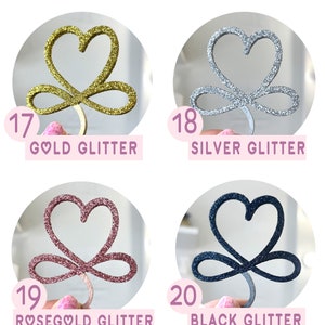 May include: Four different colors of glitter heart infinity symbols. The colors are gold, silver, rose gold, and black.