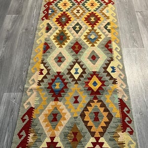 Puede incluir: Una alfombra colorida con un patrón geométrico en tonos de rojo, amarillo, azul, verde y marrón. La alfombra tiene un diseño tradicional con detalles intrincados.