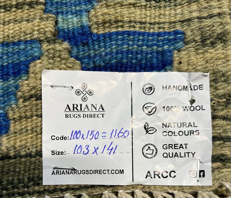 May include: A white tag with black text that reads "ARIANA RUGS DIRECT" and includes information about the rug's size, code, and material. The tag also includes the text "HANDMADE", "100% WOOL", "NATURAL COLOURS", "GREAT QUALITY", "ARIANARUGSDIRECT.COM", and "ARCC".
