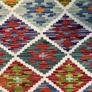 May include: A colorful woven rug with a geometric diamond pattern in shades of red, green, blue, and orange.