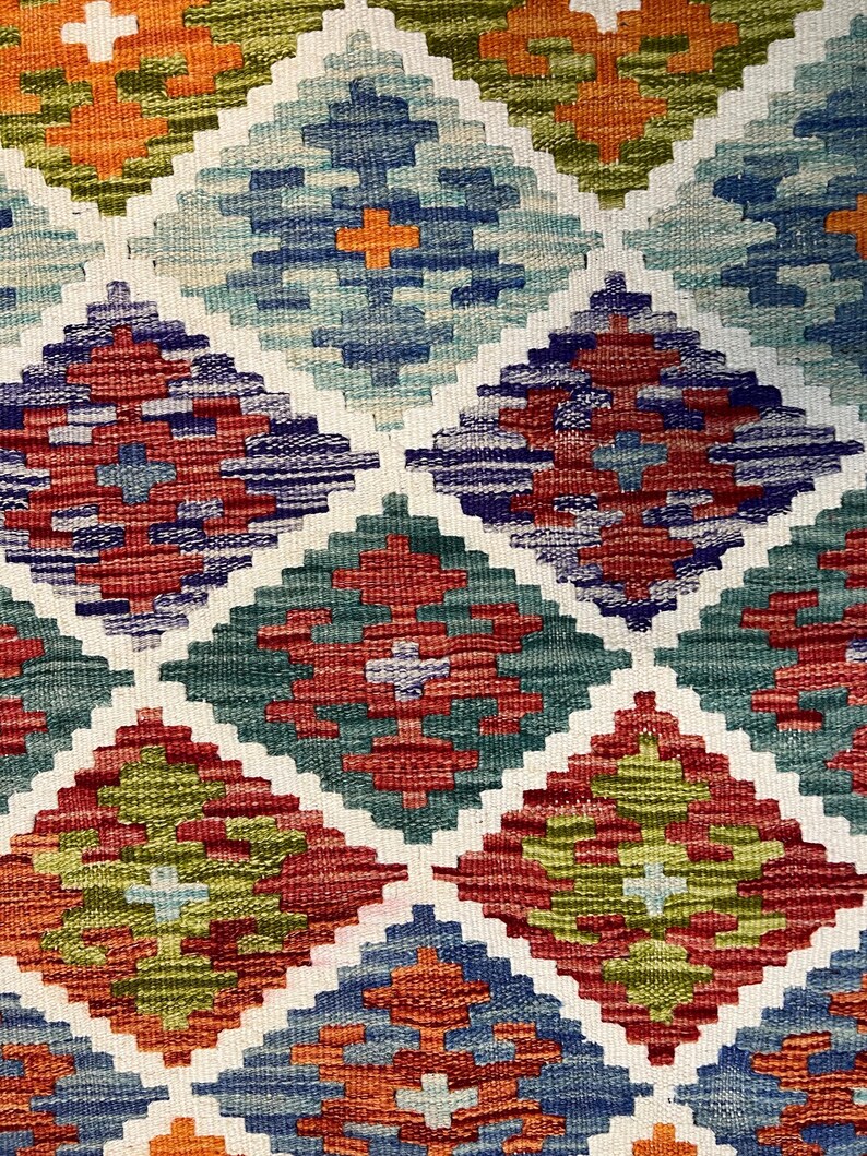 May include: A colorful woven rug with a geometric diamond pattern in shades of red, green, blue, and orange.