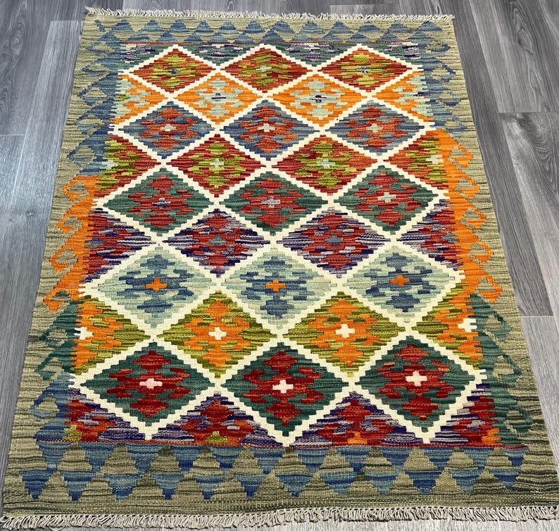 May include: A colorful rug with a diamond pattern in shades of orange, red, green, blue, and white. The rug has a fringe border.